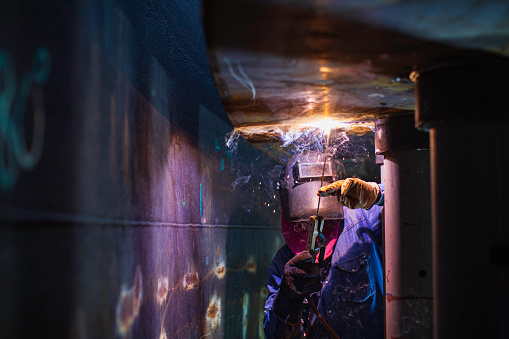 Welding male worker metal arc is part in machinery tank nozzle pipeline construction petroleum oil and gas storage tank inside confined spaces.