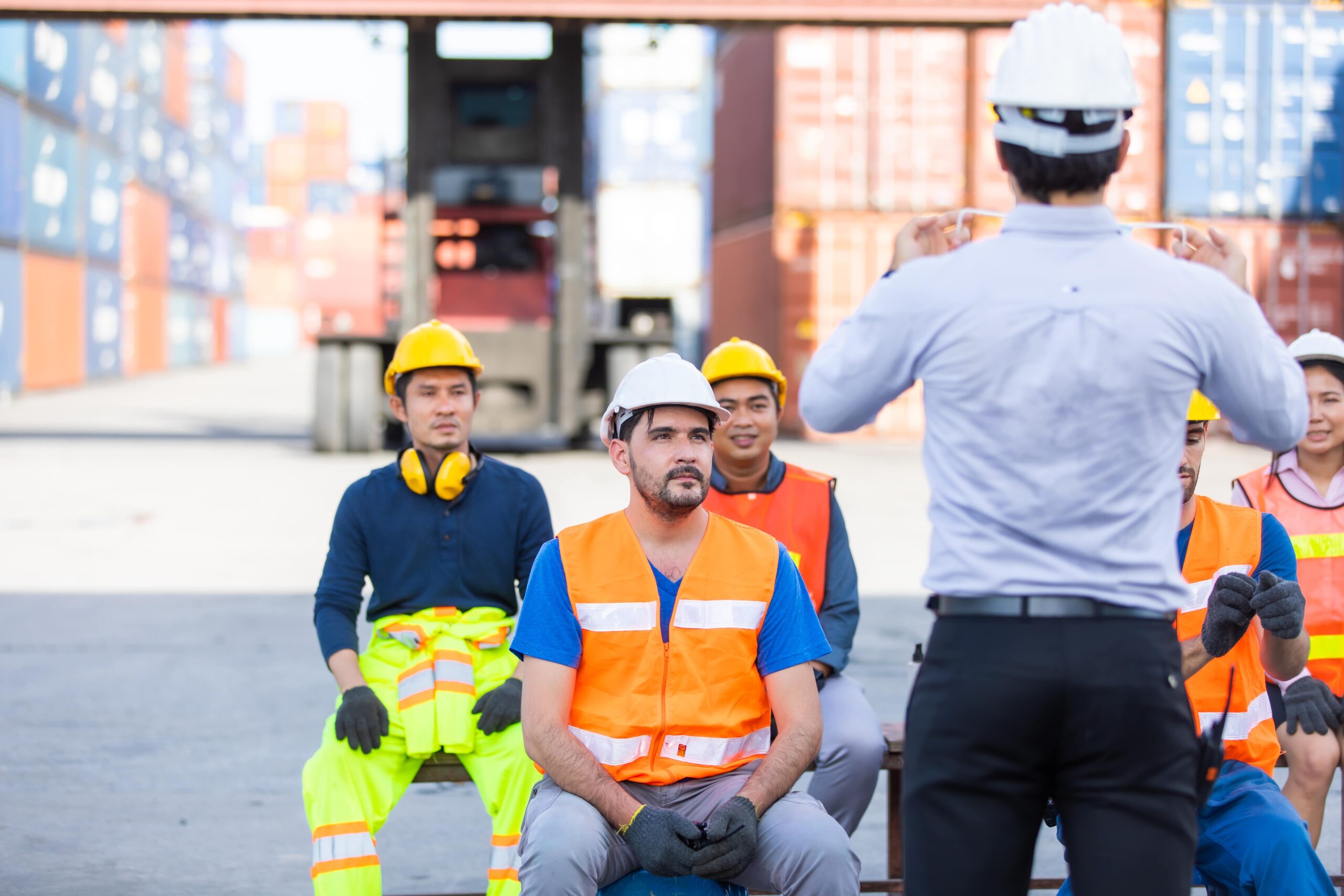 A group of individuals wearing hard hats and safety vests, engaged in a construction or safety-related activity.
